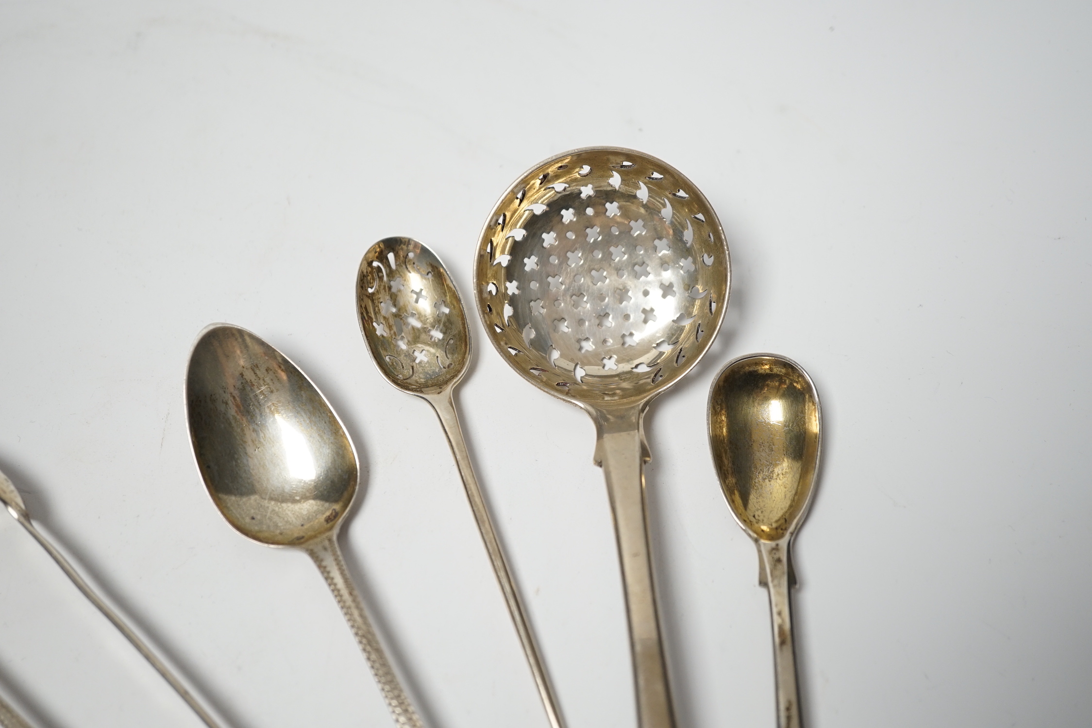 An 18th century silver mote spoon, marks rubbed, 11.8cm and five other various silver spoons and a pair of silver sugar tongs, 5.1oz.